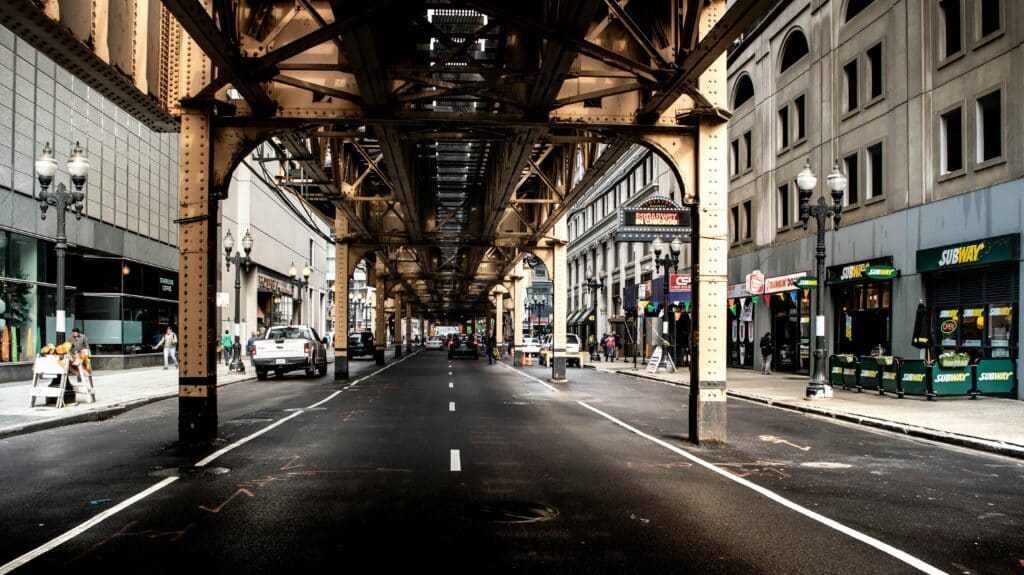 Vibrant view of a Chicago street beneath the elevated train tracks capturing city life and architecture.