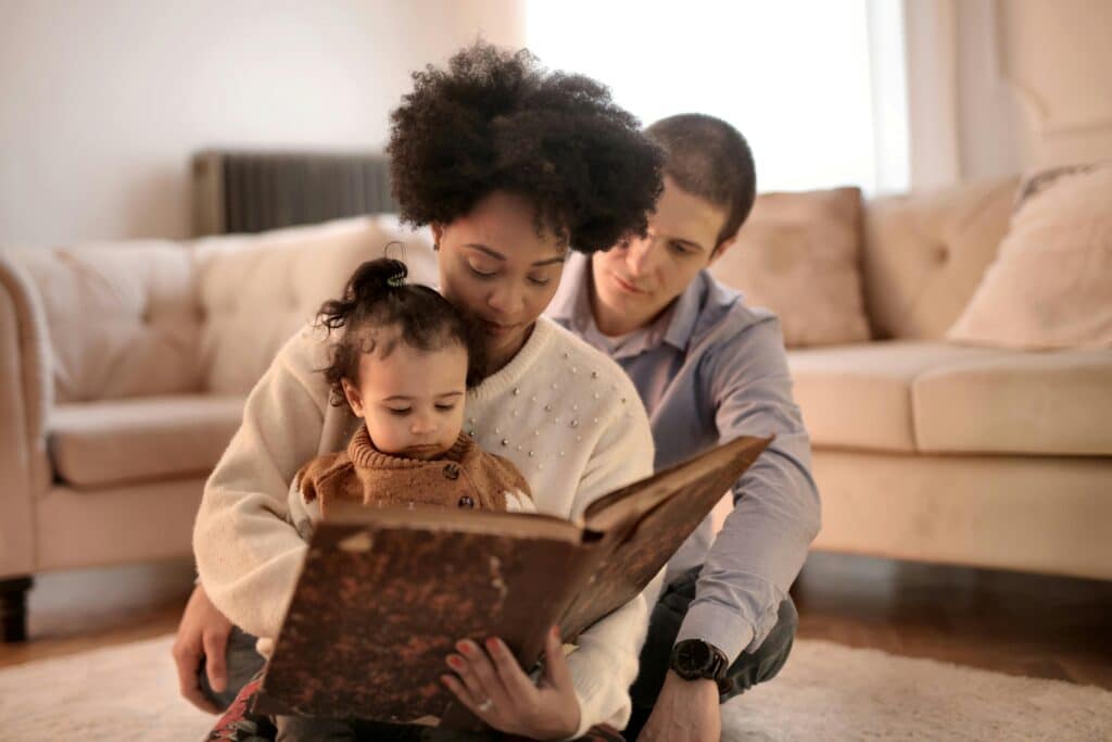 Mother, father, and child enjoying a storybook together in their cozy living room.