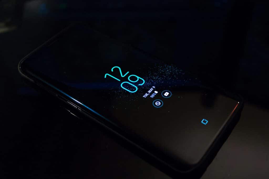 Close-up of a smartphone in the dark displaying digital clock and notifications.