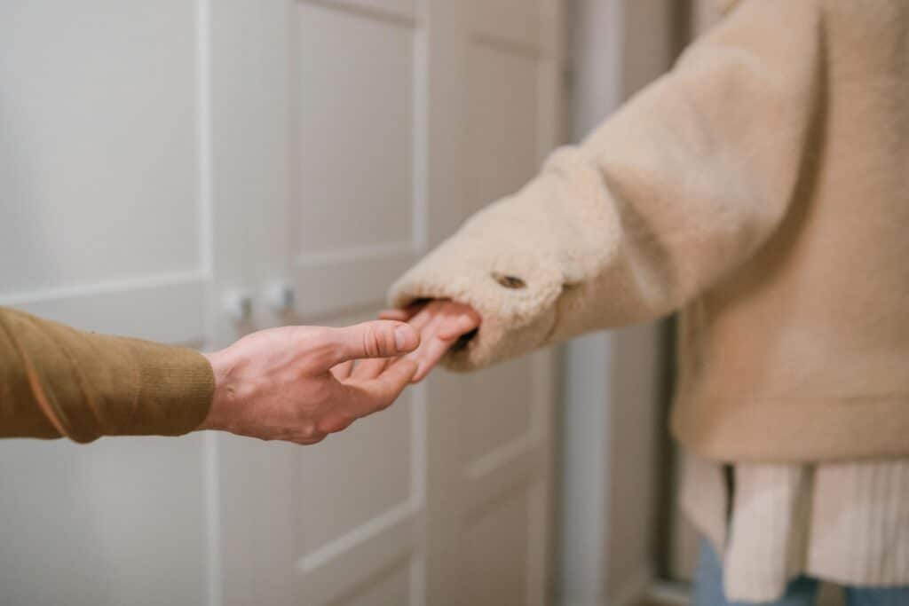 Close-up of two people holding hands indoors, indicating connection and support.