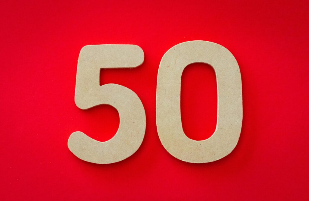 Close-up of cardboard cutout number 50 on a vivid red backdrop, symbolizing celebration or milestone.