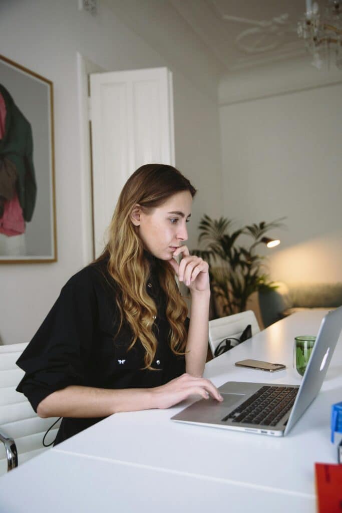 Woman deeply focused on working at a laptop in a stylish home office setting.