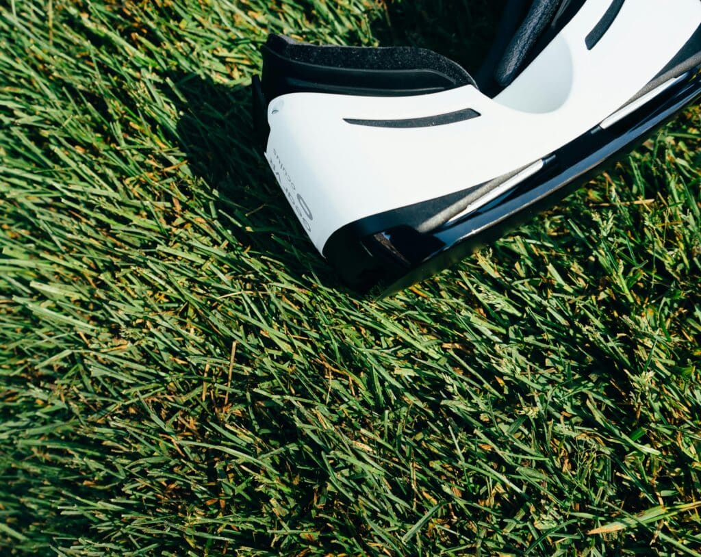 A close-up shot of VR goggles placed on a green grass lawn under sunlight.