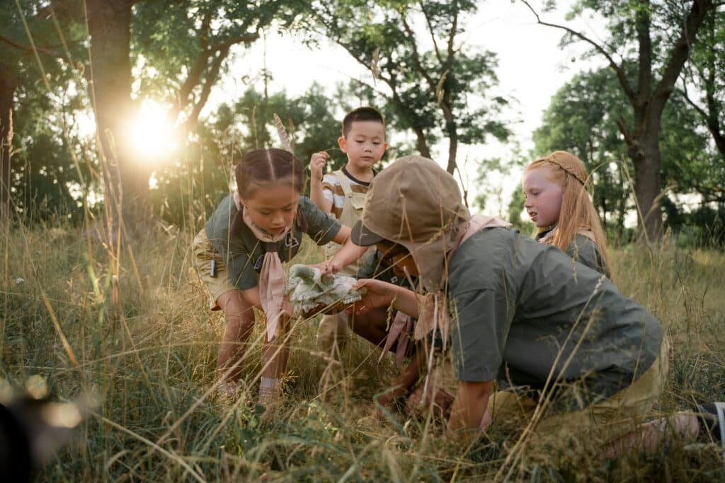 Curious children discover an animal skull in a sunlit forest during summer camp.