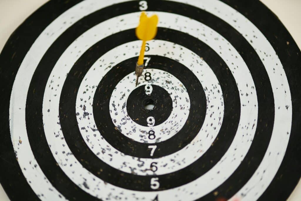 pexels-photo-1552617-1552617 Close-up of a dart hitting the bullseye on a black and white target board symbolizing success.