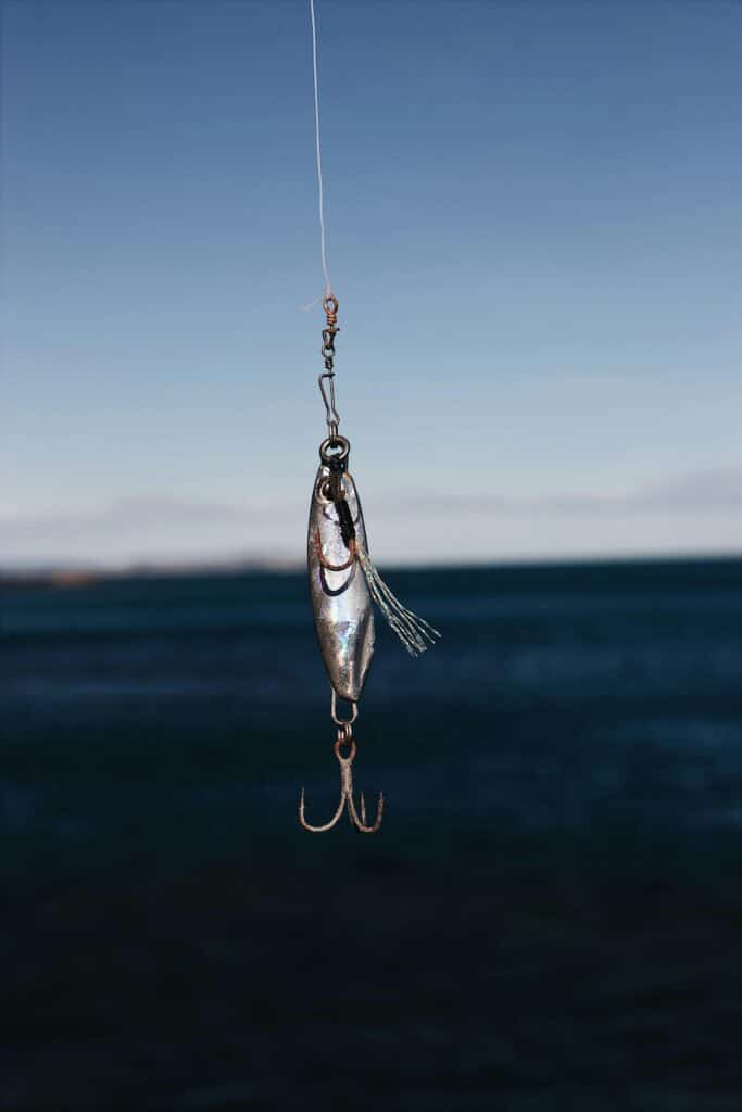 Close-up of a fishing lure hanging against a clear blue sea backdrop, ideal for outdoor and fishing themes.