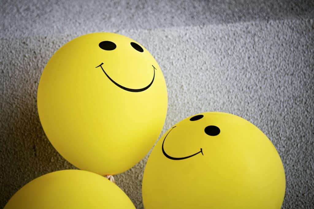 Three yellow smiley face balloons creating a cheerful and bright atmosphere indoors.