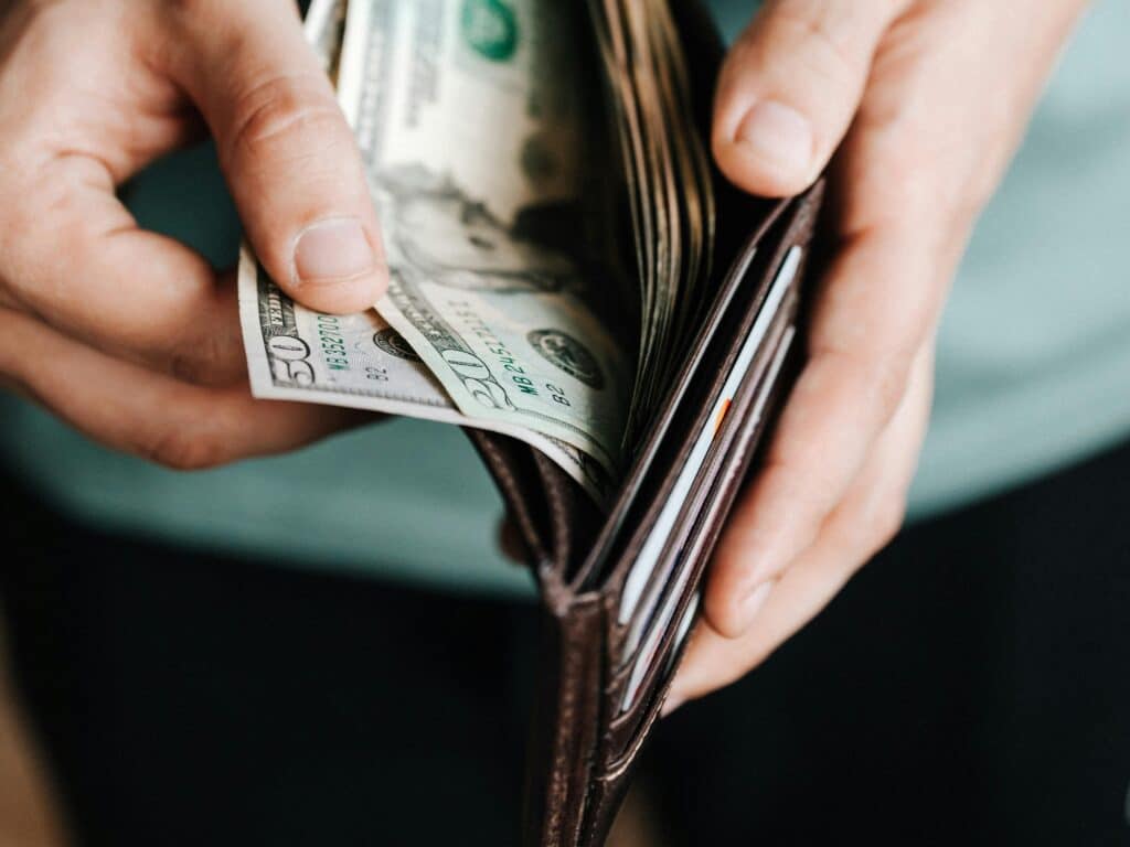 Close-up of hands holding a wallet with cash, depicting financial management.