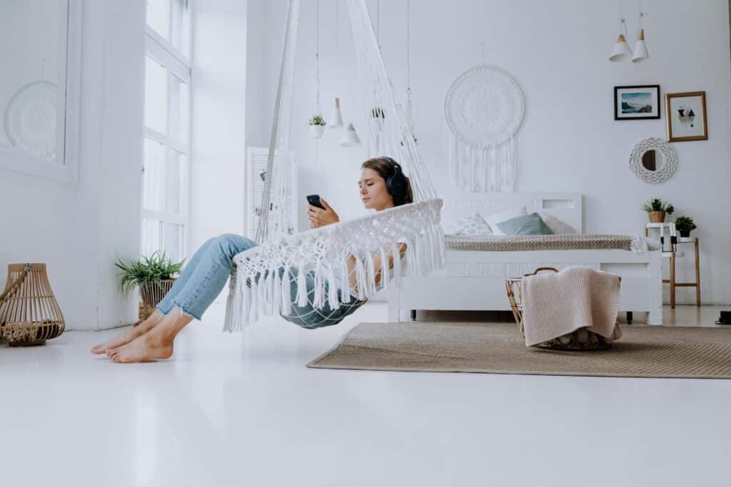 A young woman listening to music in a minimalist bedroom, enjoying a relaxed atmosphere.