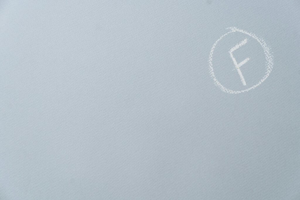 Chalk-written F grade encircled on a textured light blue surface.