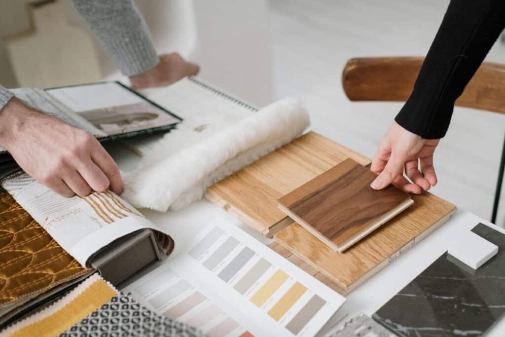 pexels-photo-6583355-6583355 Hands selecting and comparing textile and wood samples for interior design.