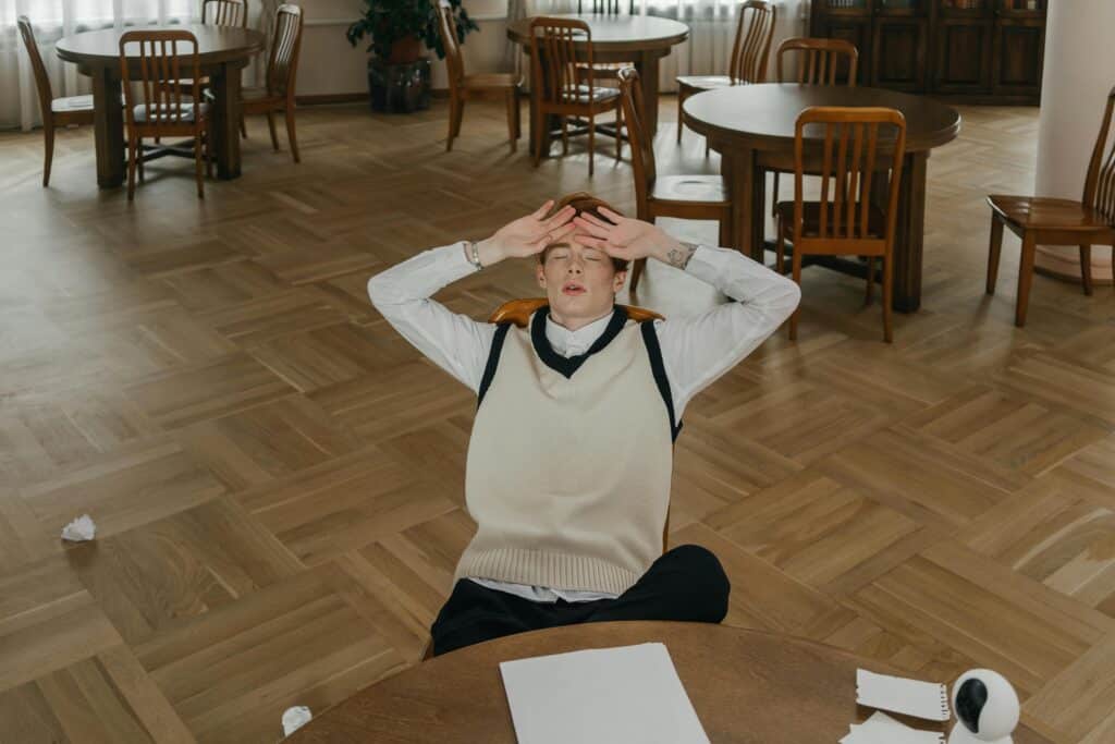 Young man feeling stressed and overwhelmed while studying in a library setting.
