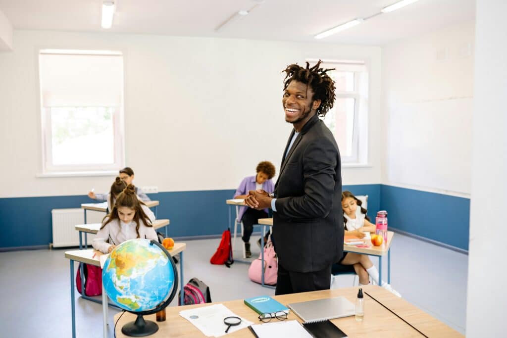 Teacher engaging with students in a bright classroom, promoting a positive learning environment.