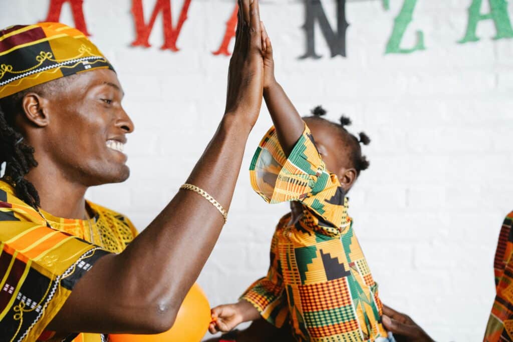 Father and daughter share a joyful moment celebrating Kwanzaa with a high five.
