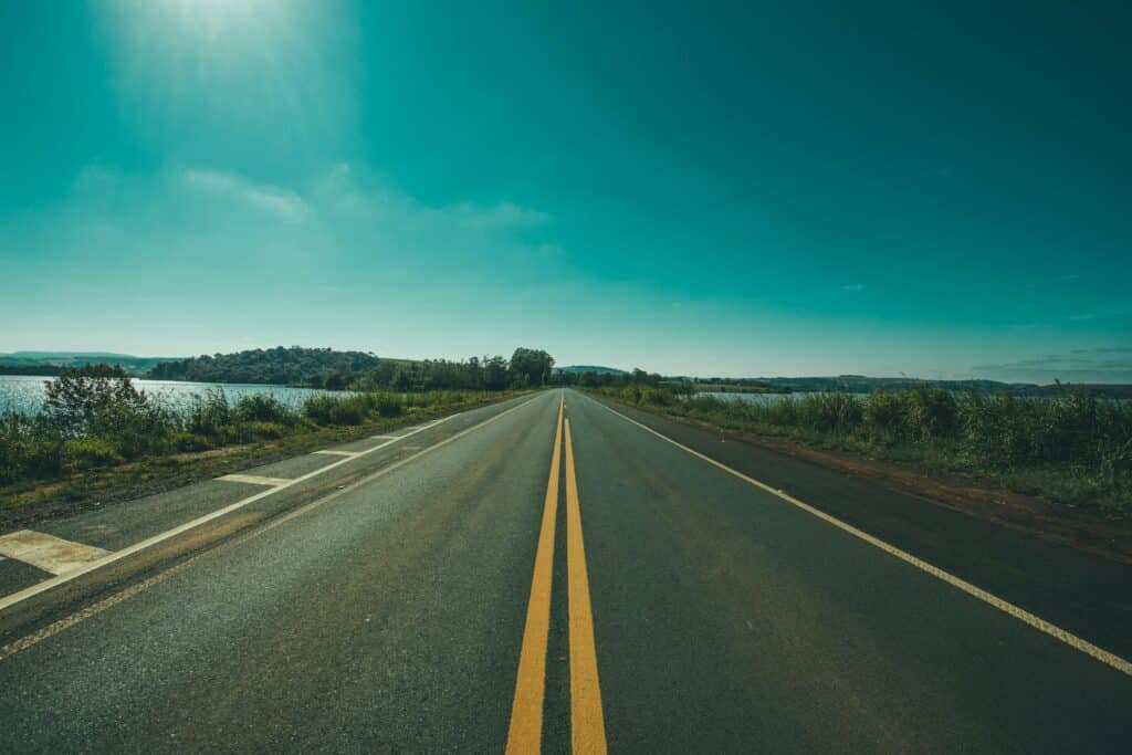 A tranquil highway stretches into the horizon under a clear blue sky, offering a serene travel vibe.