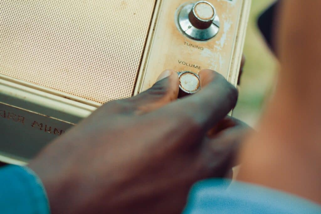 Hand adjusting volume on a vintage radio in an outdoor setting.