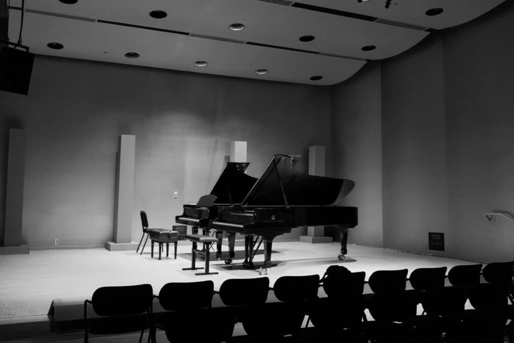 Black and white photograph of an empty concert hall featuring a grand piano on stage in Montreal.