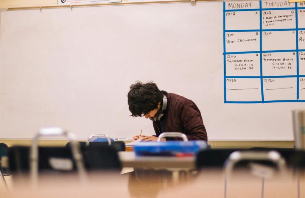 A high school student studying and solving problems in a classroom setting.