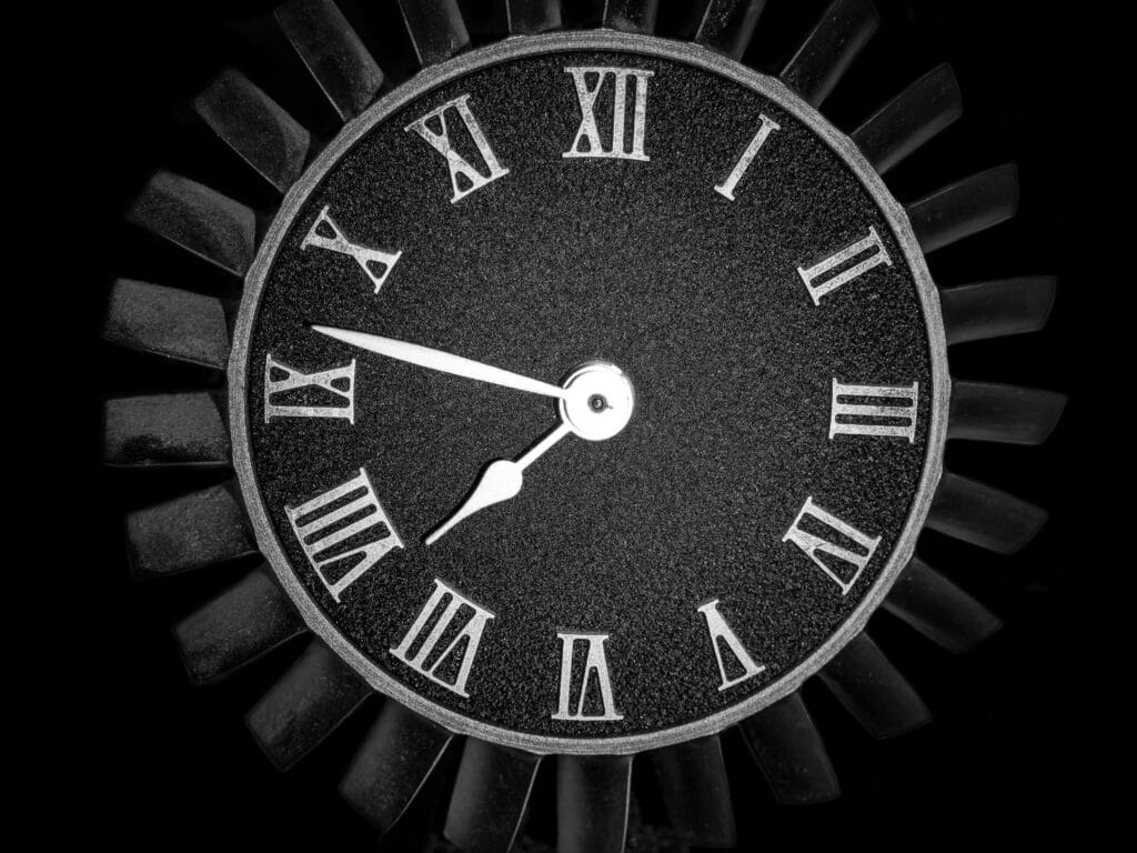 Stylish black clock with Roman numerals against a dark background.