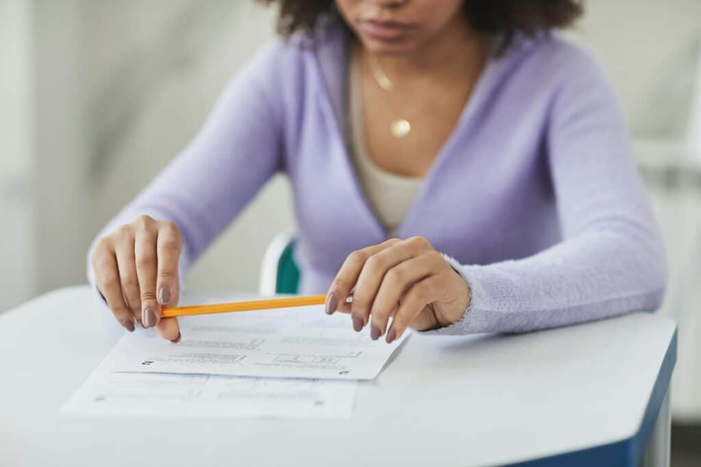A focused student in a classroom setting, holding a pencil and an exam paper.