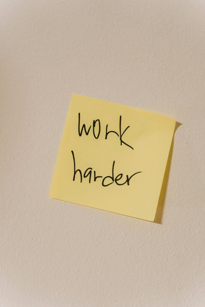 A yellow sticky note with the message 'work harder' inspires productivity in a workspace.