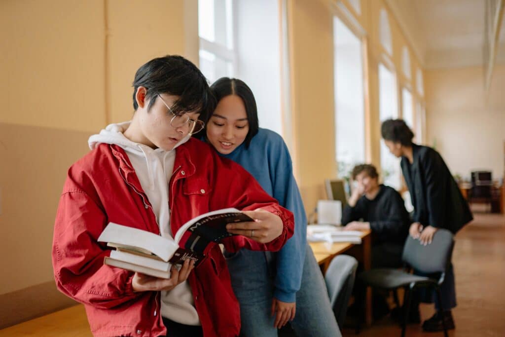 Group of students reading and studying together in a library setting.