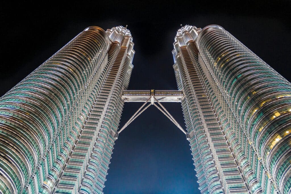 Stunning low-angle shot of the iconic Petronas Towers in Kuala Lumpur, Malaysia, illuminated against the night sky.