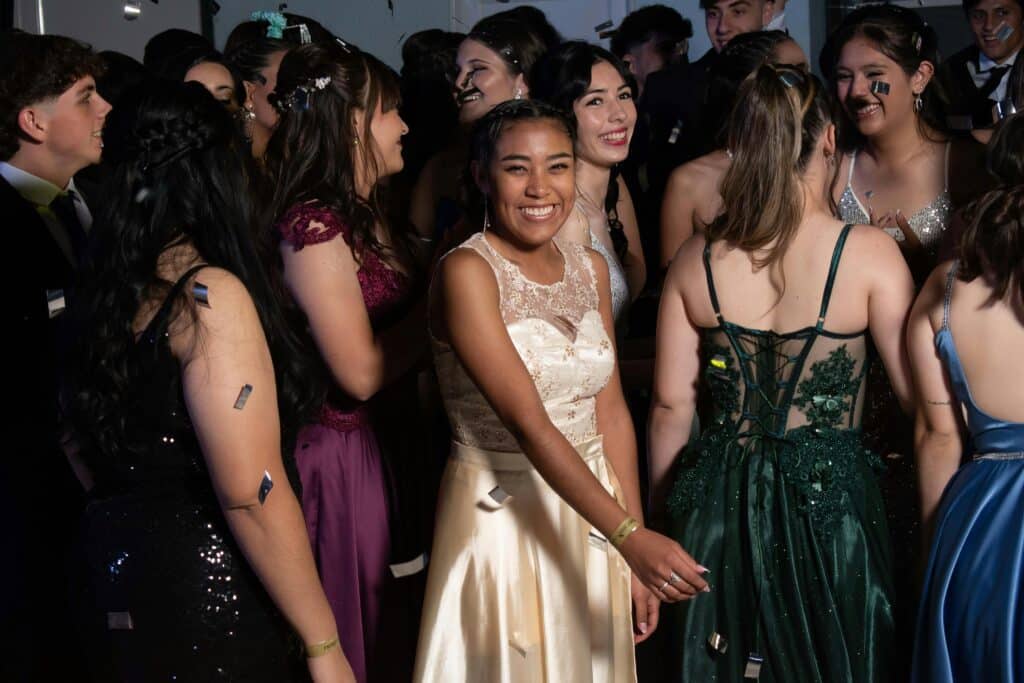 A group of teenagers enjoying a lively party with colorful dresses and smiling faces.