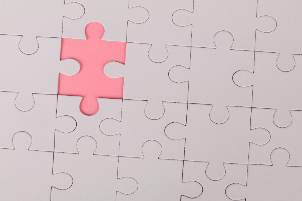 Close-up of an unfinished puzzle with a pink missing piece, highlighting emptiness.