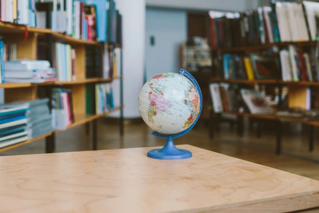 A globe in a quiet library setting, surrounded by shelves filled with books, represents education and exploration.
