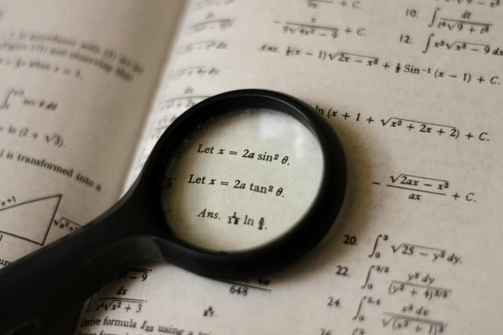 A magnifying glass focusing on mathematical equations in a textbook, symbolizing detailed study.
