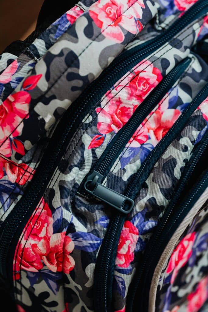 Close-up view of a floral patterned backpack with prominent zippers.