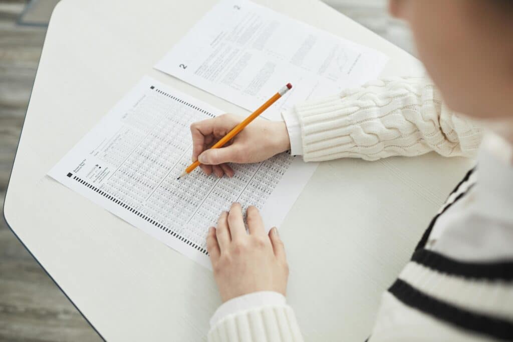 Close-up of a student filling out a multiple-choice exam in a quiet classroom setting.