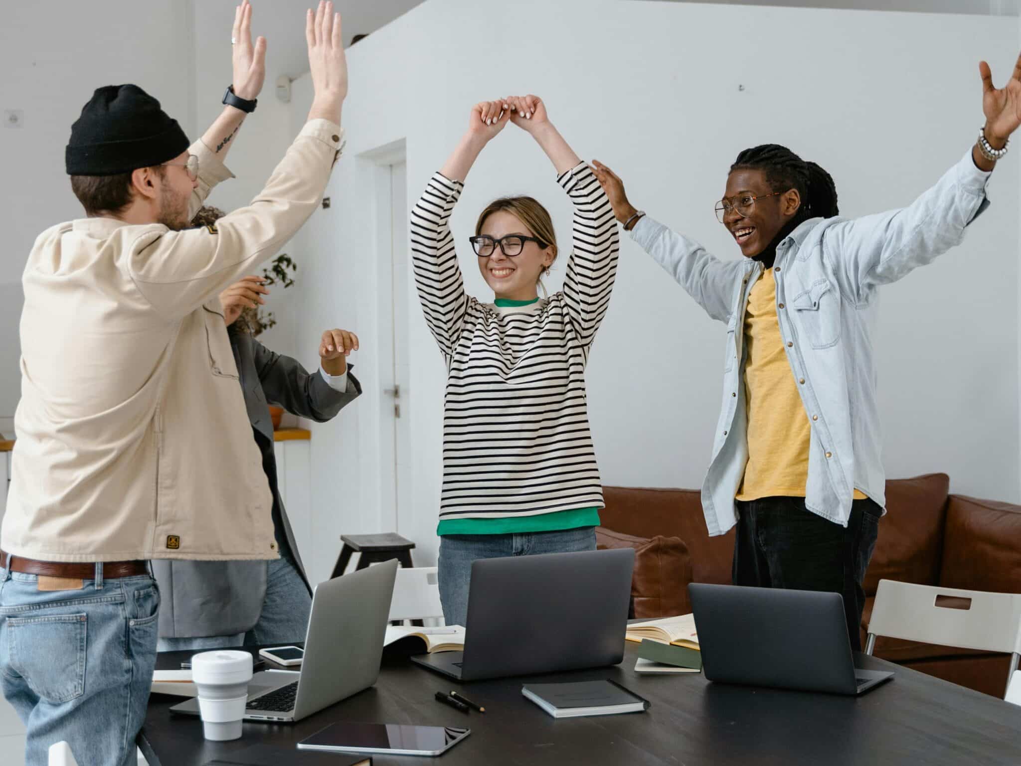 A multicultural group of professionals celebrating success in a modern office setting, emphasizing teamwork and collaboration.