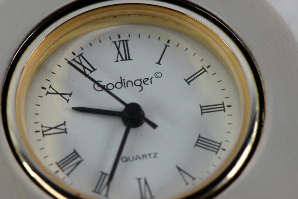 Detailed close-up of a Godinger quartz clock with classic Roman numerals and clock hands.