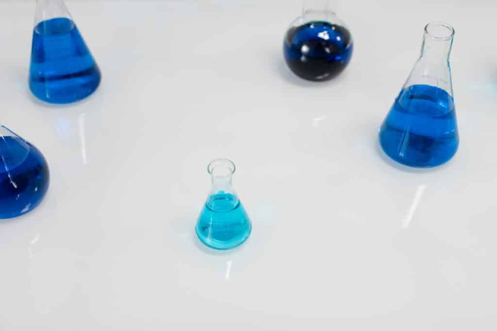 Various glass flasks filled with blue liquid in a scientific setting, perfect for research themes.