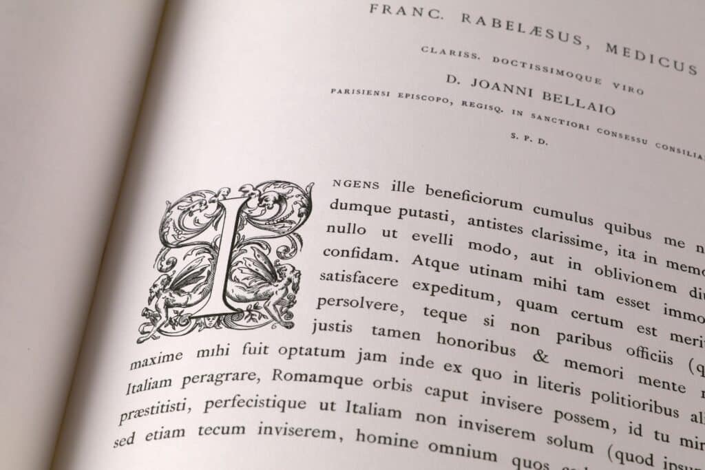 Close-up of an open book with intricate Latin text and decorative initials.