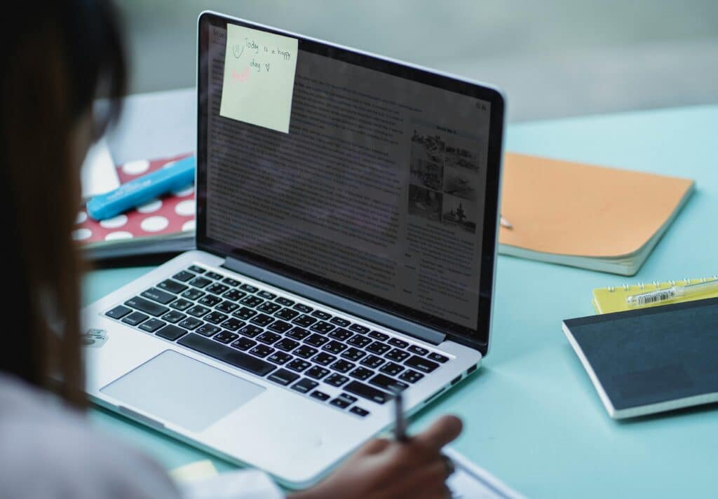 A student working on a laptop with notebooks, focusing on studying.
