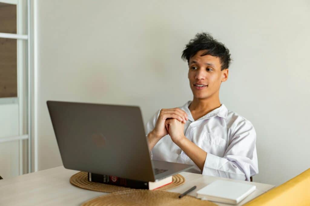Young man in casual attire attentively participating in an online class from home.