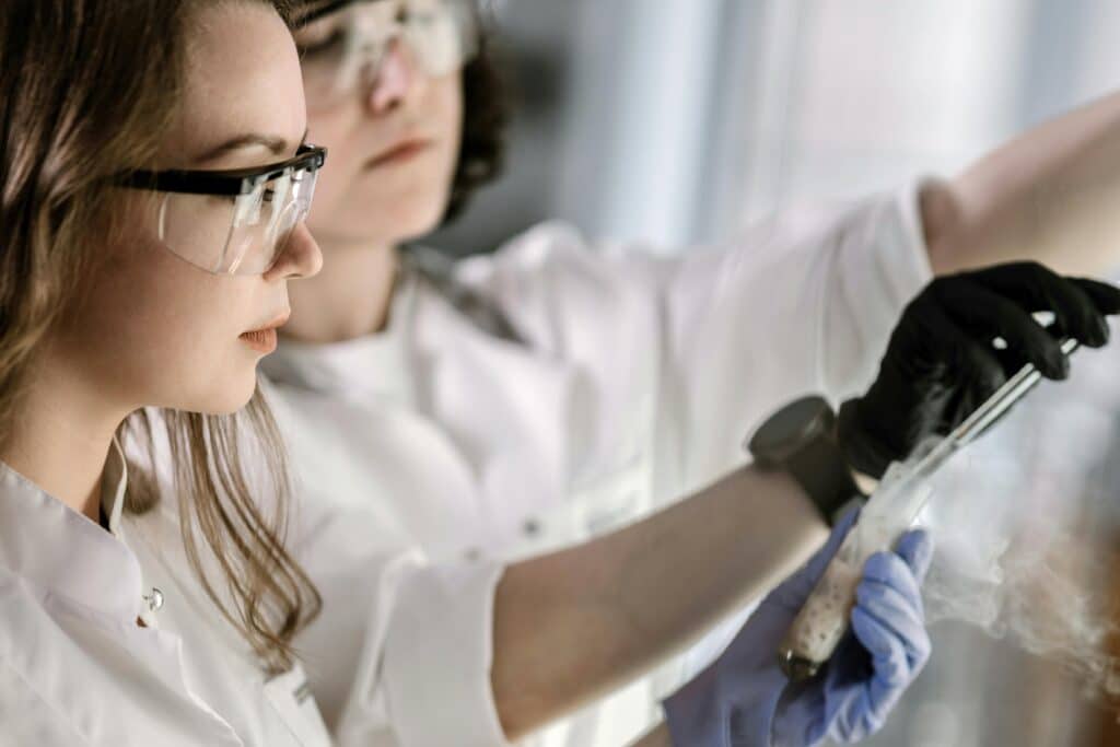 Two scientists in protective gear conducting a chemical experiment in a laboratory.