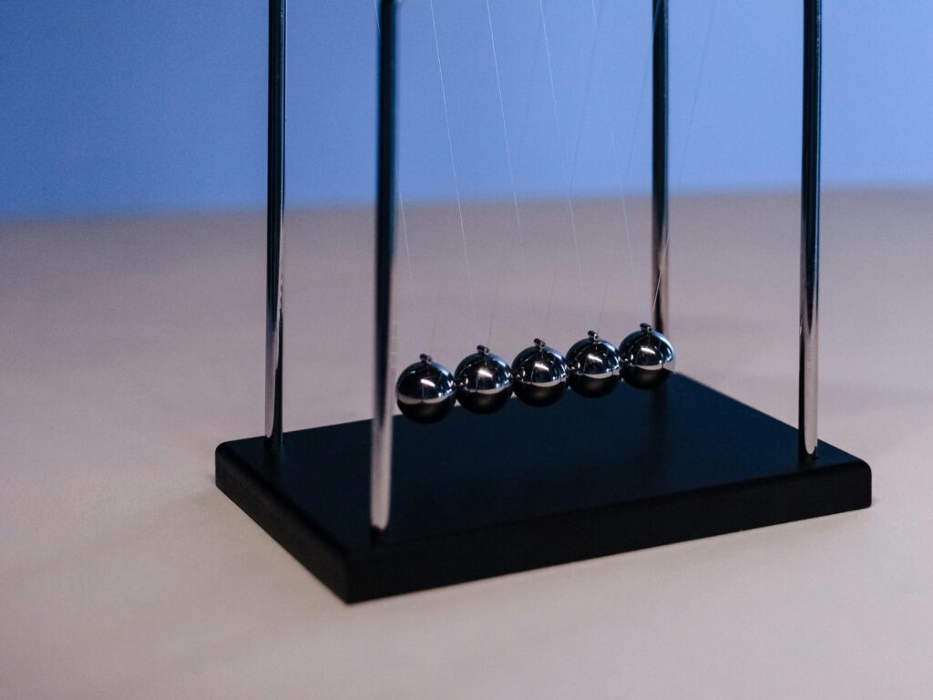 Studio shot of a Newton's cradle on a blue gradient background, illustrating physics concepts.