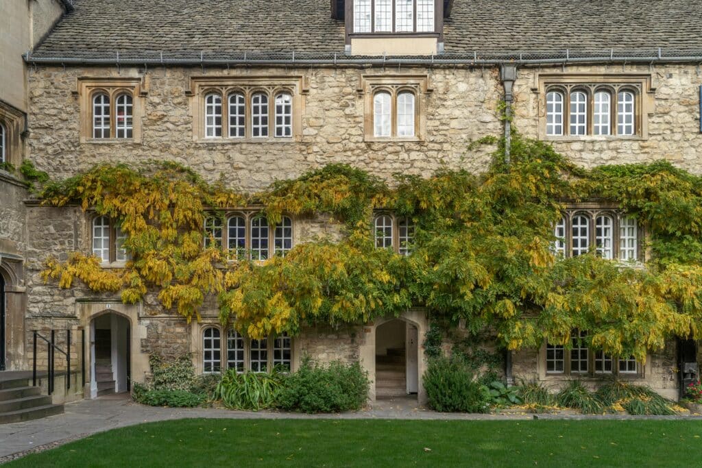 Charming ivy-covered stone facade of an Oxford historic building with traditional windows.