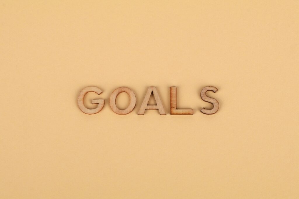 Wooden letters spelling 'GOALS' on a plain background, emphasizing motivation.