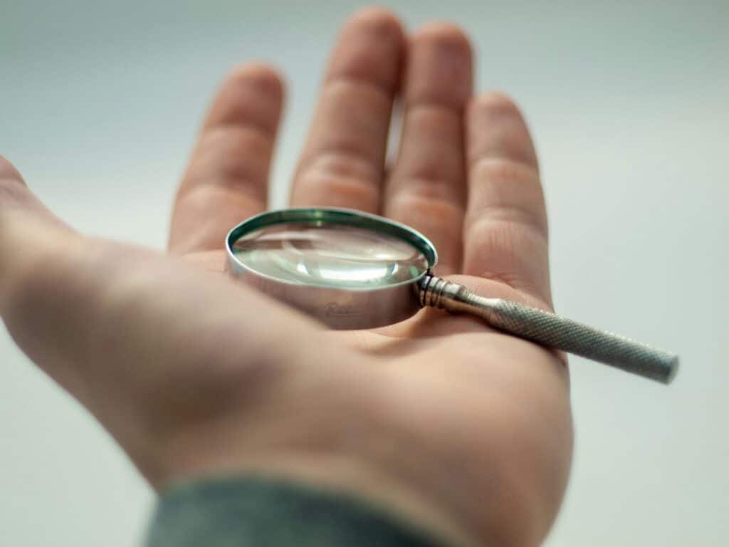 A detailed close-up of a hand holding a magnifying glass, showcasing precision and focus.