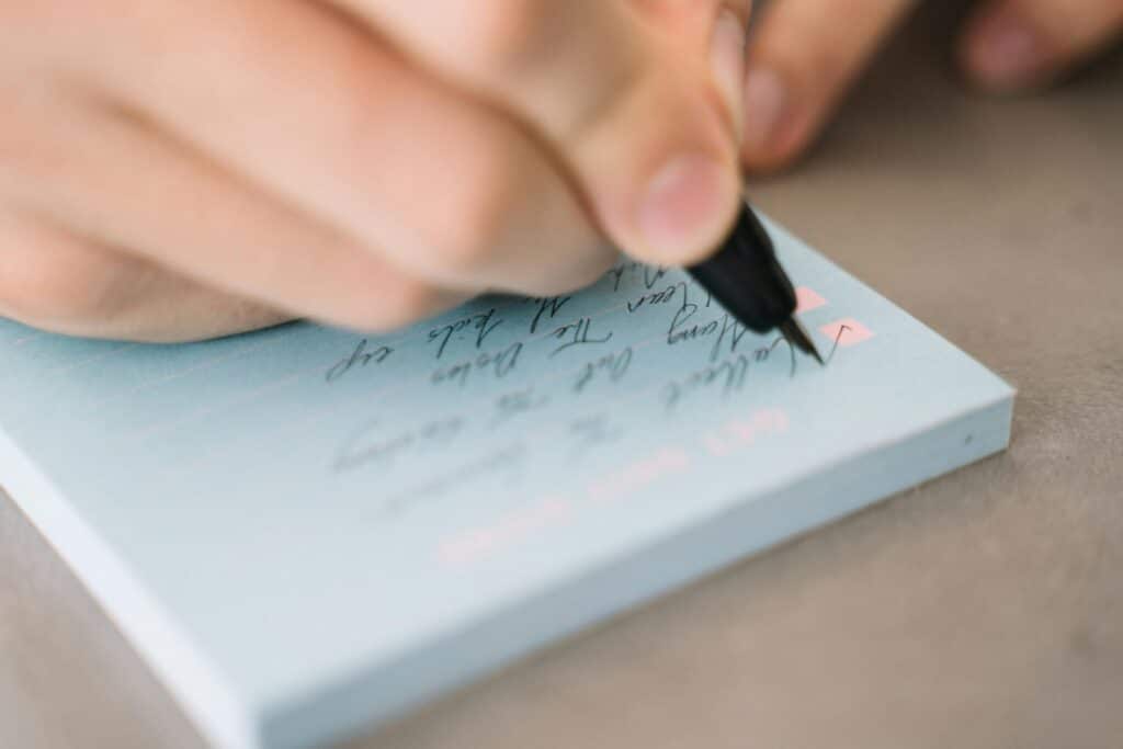 A close-up view of hand writing on a notepad, focusing on handwriting details.