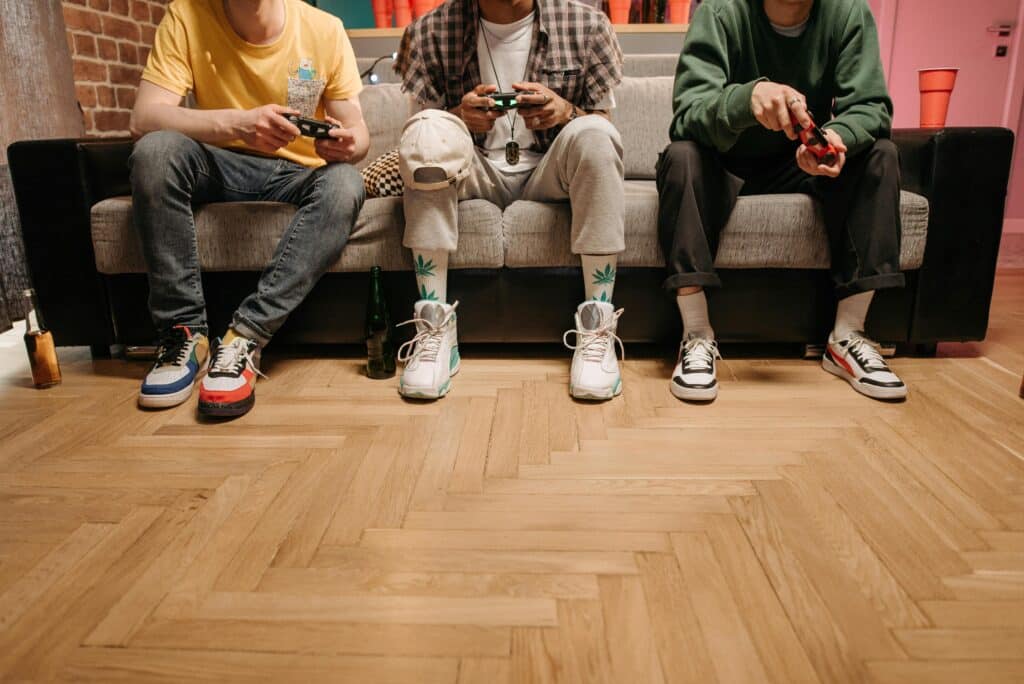 Three men sitting on a sofa playing video games, focused and enjoying the game.