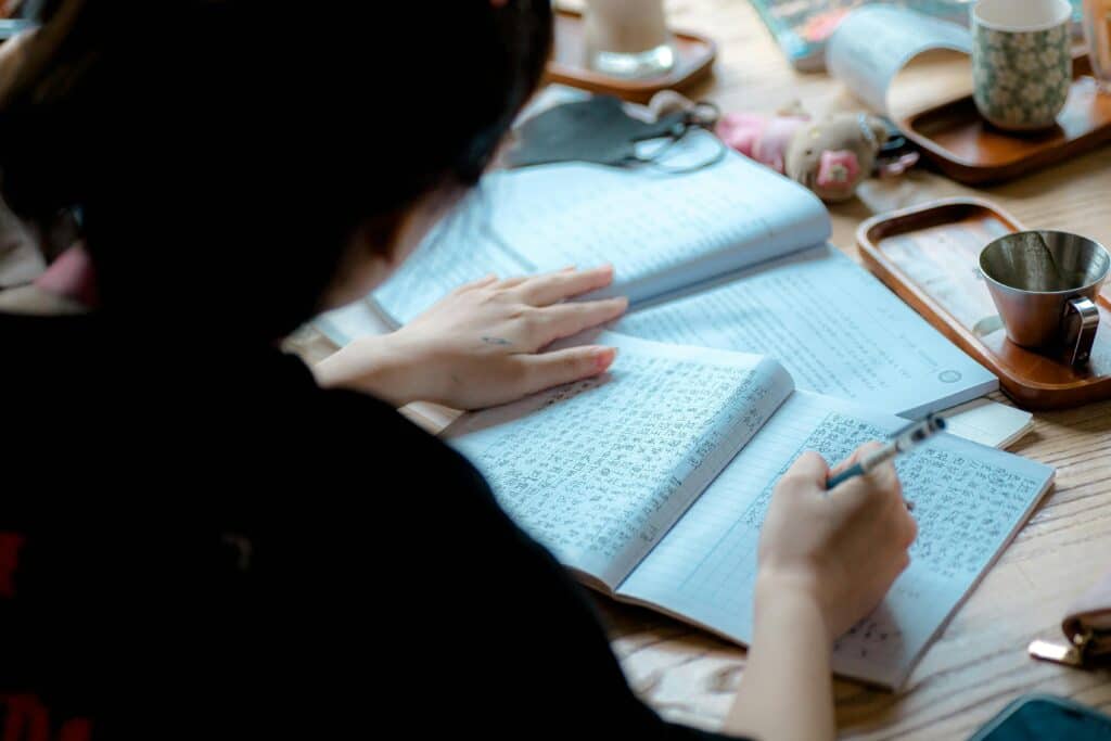 A person studying and writing in a notebook with focus on learning and education in a peaceful setting.